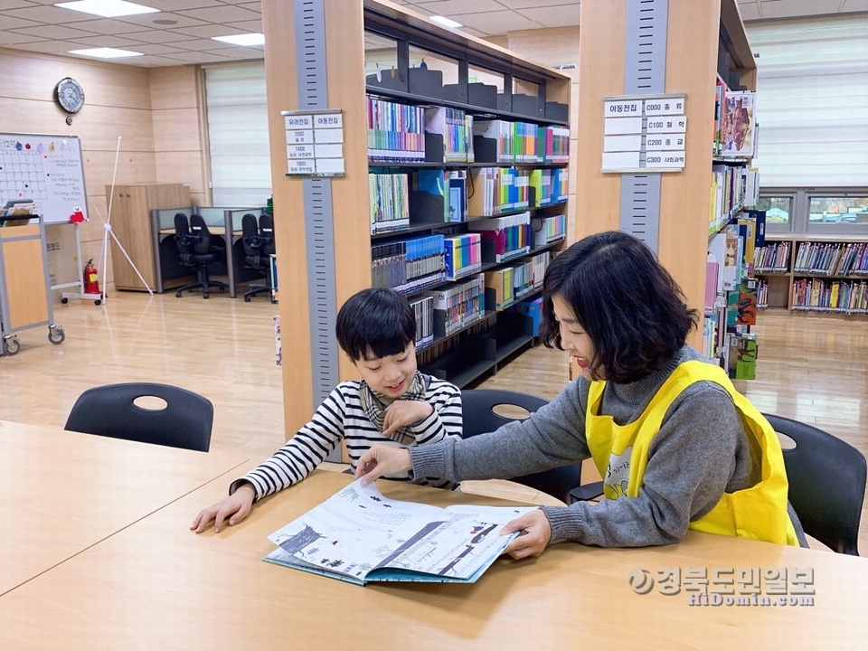 도서관을 찾은 한 어린이가 도서 안내를 받고 있다.