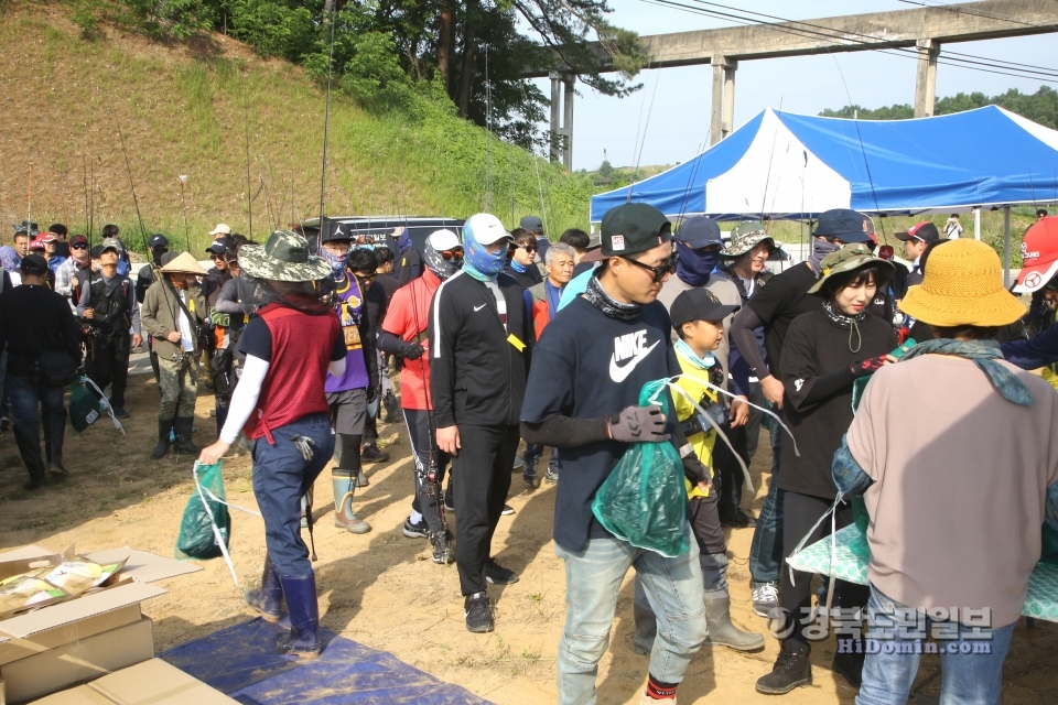 “손 맛 느끼러 가자” 낚시에 앞서 준비물을 받기위해 줄서있는 강태공들. 어른들 사이에 어린이 강태공도 보인다.