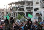 팔레스타인 무장정파 하마스 대원들이 27일(현지시간) 가자시티에서 파괴된 집들과 주민들 사이에 무기를 들고 포즈를 취하고 있다.연합