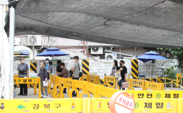 일요일 확진자 기준으로 역대 최다치를 기록한 19일 서울 강북구 시범공영주차장에 마련된 임시선별진료소에서 시민들이 검사를 위해 줄을 서있다. 뉴스1