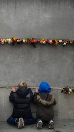 독일 베를린 장벽 붕괴 25주년을 맞은 9일(현지시간) 기념 보존용 베를린장벽 밑에 어린이 두 명이 무릎꿇고 앉아 장벽 틈 사이에 꽂힌 장미꽃들을 바라보고 있다. 이날 앙겔라 메르켈 독일 총리도 이곳을 찾아 당시 희생자들을 추도하는 의미로 장미를 헌화했다. 연합