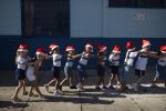 17일(현지시간) 브라질 리우데자네이루에서 산타클로스 모자를 한 초등학교 저학년 어린이들이 줄지어 앞에 있는 친구 어깨에 손을 얹은 채 산타의 도착을 기다리고 있다. 연합