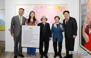 칠곡할매글꼴 특별 기획전 개막식에서 전이수 작가의 작품을 배경으로 기념촬영을 하고 있다. 전이수 작가는 자신을 작품을 칠곡할매글꼴로 설명한 캔버스를 들고 있다.