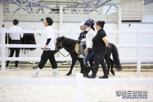 교관의 설명을 듣고 참가자들이 조랑말을 타고 걷기 훈련 받고 있다.