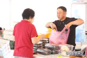 한 상인이 손님에게 상품을 포장해 주면서 흐뭇한 표정을 짓고 있다