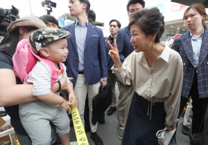 박근혜 전 대통령이 25일 오전 대구 달성군 현풍시장에서 엄마와 함께 시장에 나온 아기와 인사 나누고 있다. 뉴스1